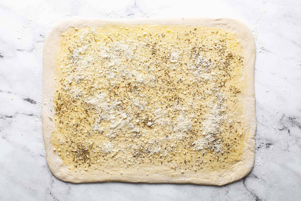 Pizza dough spread with olive oil and seasoned with dried herbs and Parmesan cheese. 