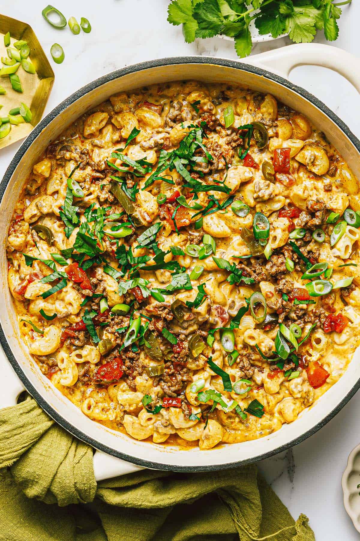 Large pan filled with creamy taco mac and cheese garnished with green onions.