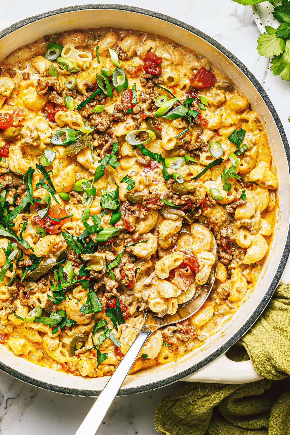 Large pan filled with creamy taco mac and cheese garnished with green onions.