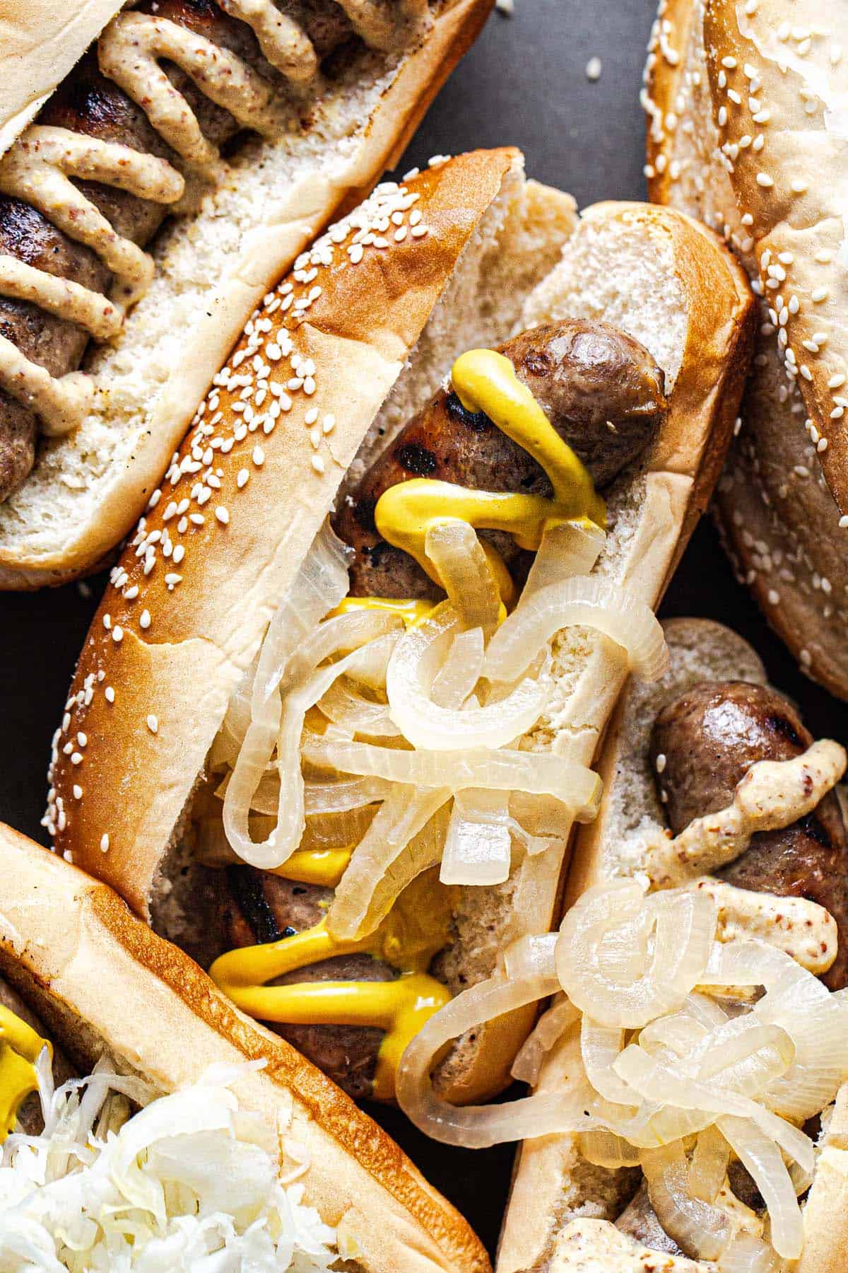 Close up shot of a brat topped with mustard and onions. 