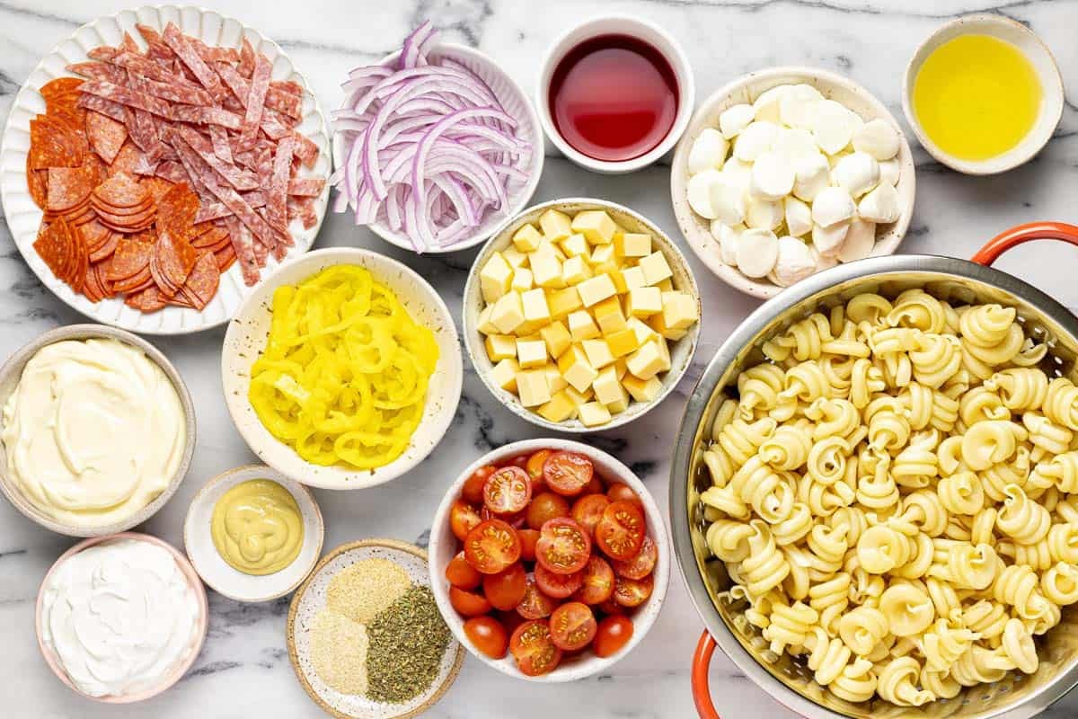 Bowls of ingredients to make Italian grinder pasta salad. 