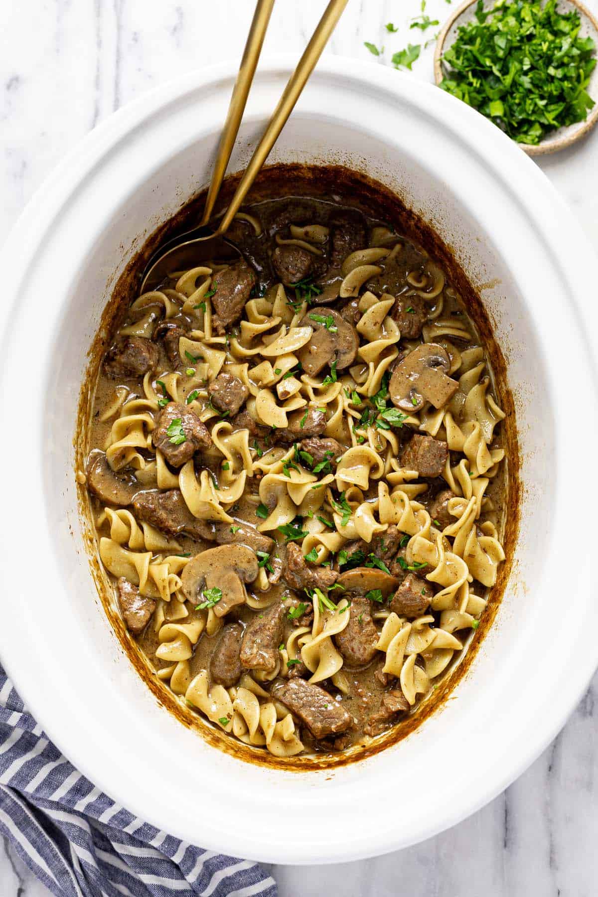 Large slow cooker with creamy beef, mushrooms, and noodles. 
