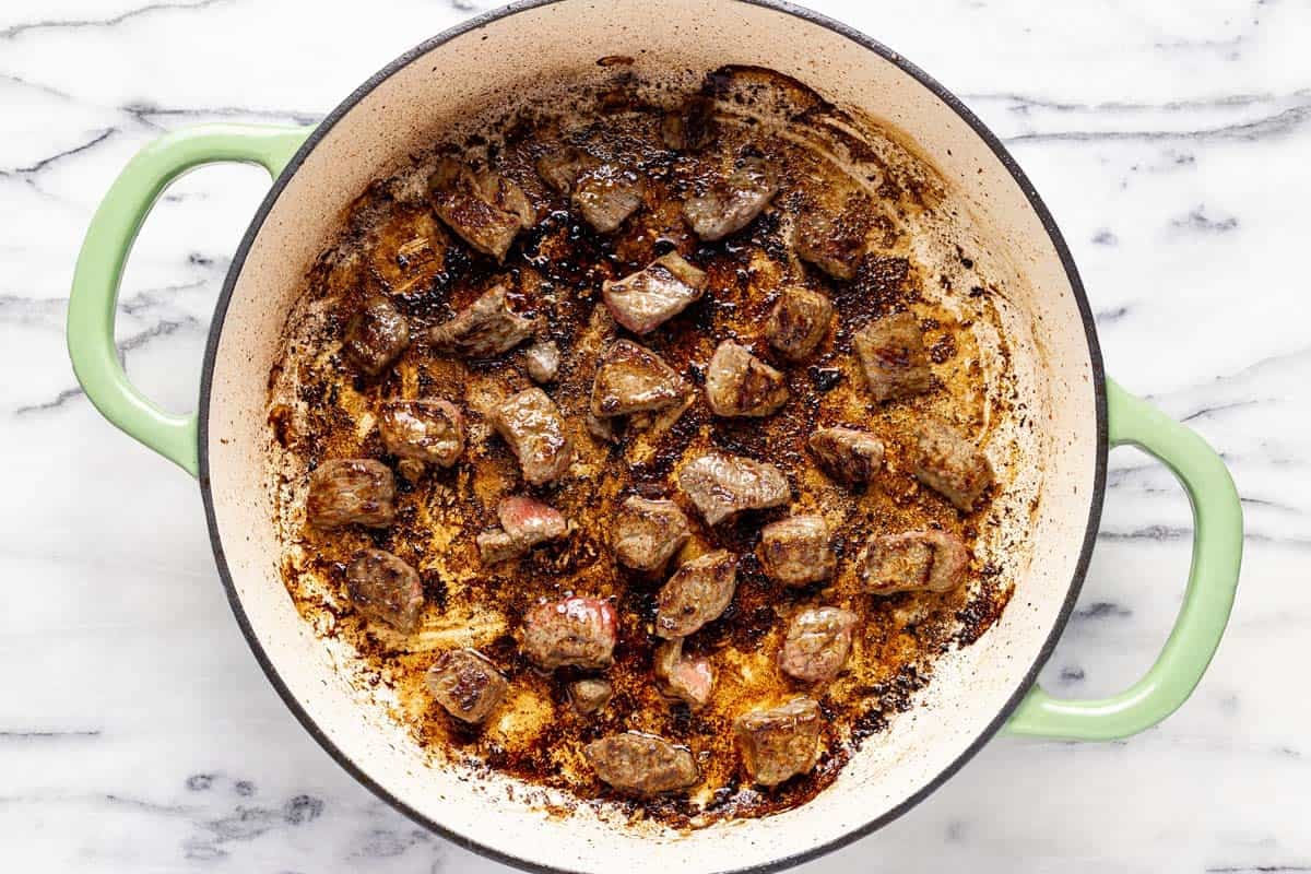 Seared stew meat in a large saute pan. 