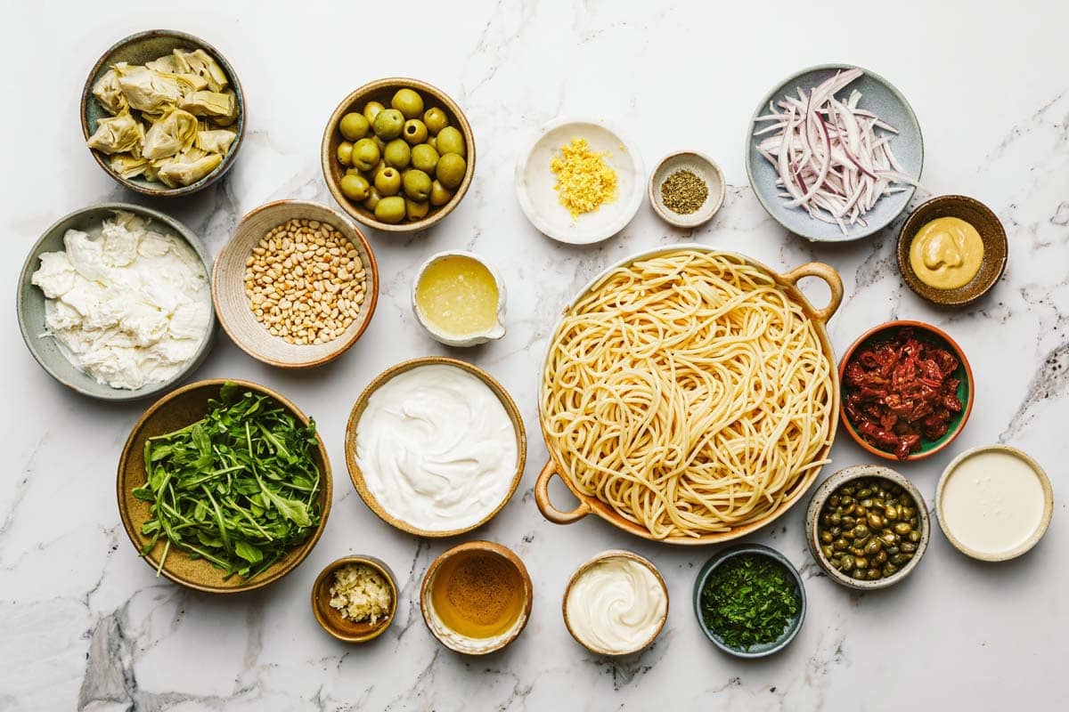 Bowls of ingredients to make Greek spaghetti salad.