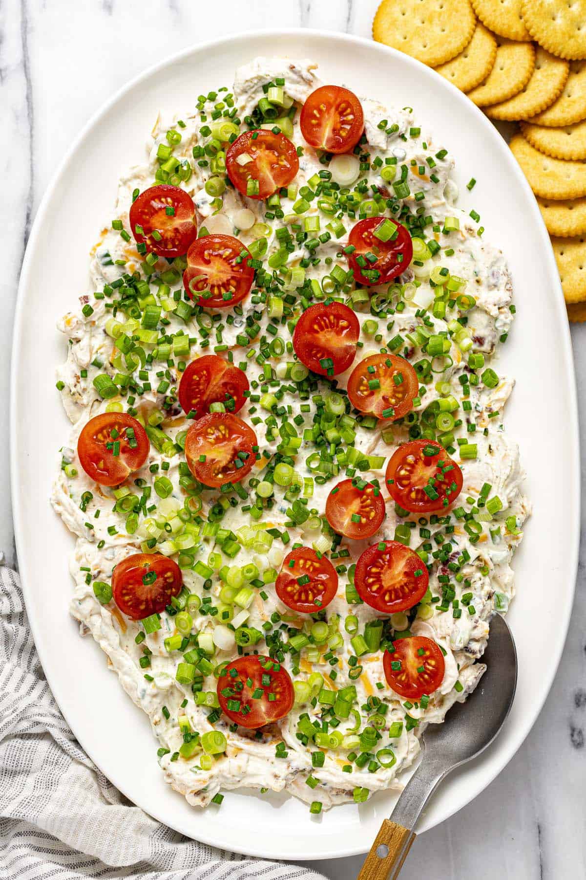 Large serving platter with creamy BLT dip topped with green onions and tomatoes. 