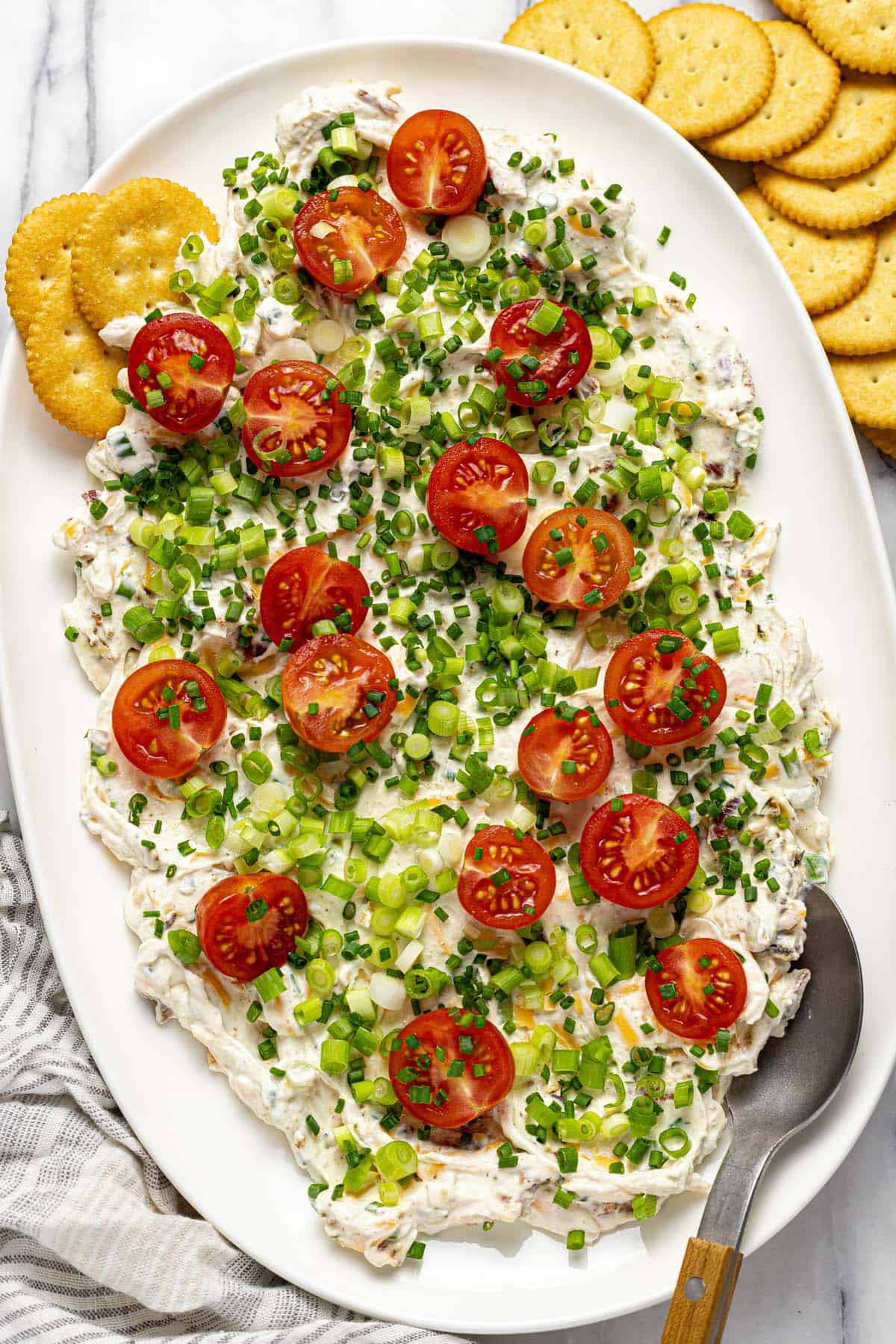 Large serving platter with creamy BLT dip topped with green onions and tomatoes. 