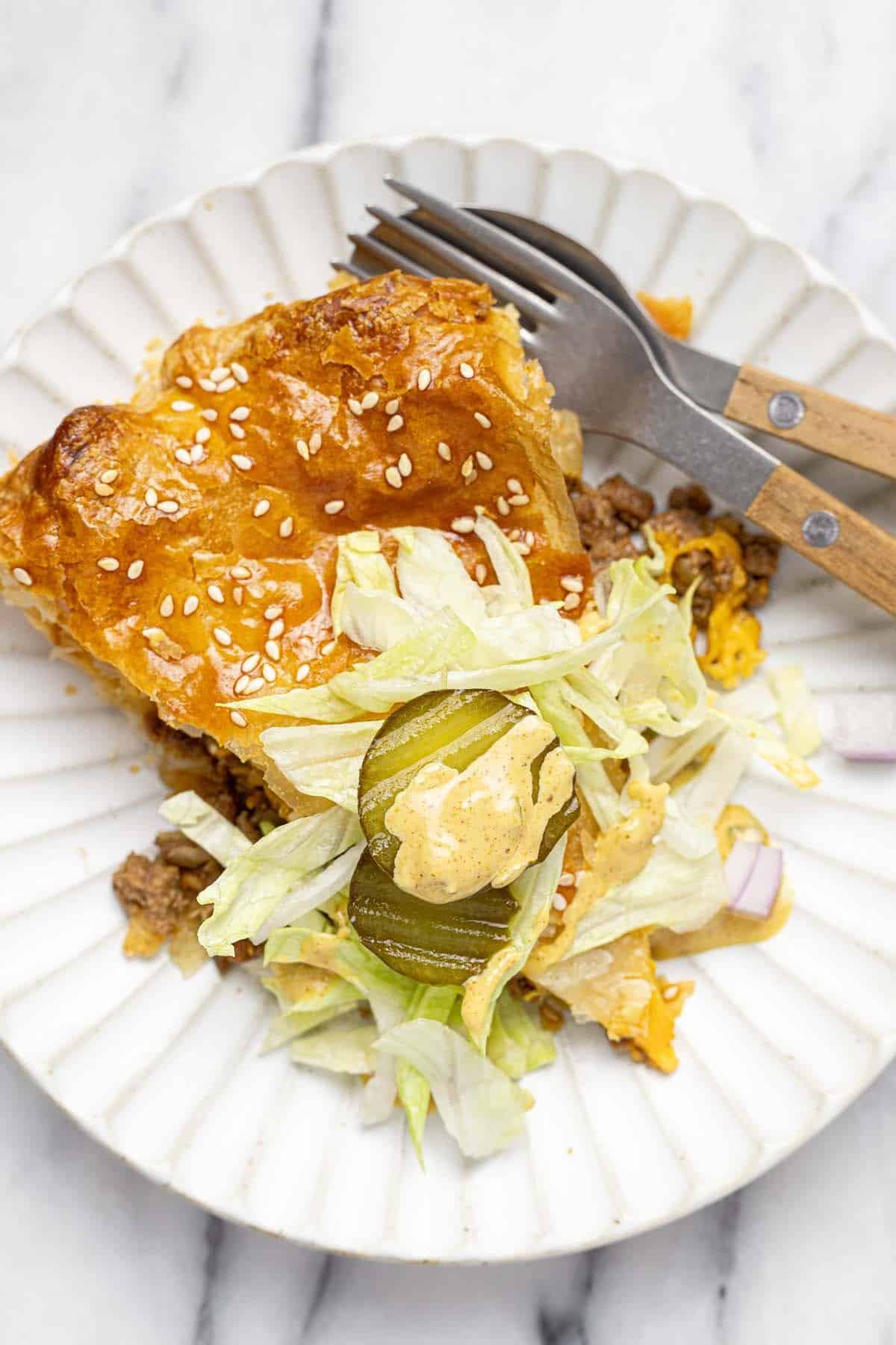 Slice of cheeseburger pie garnished with burger toppings. 