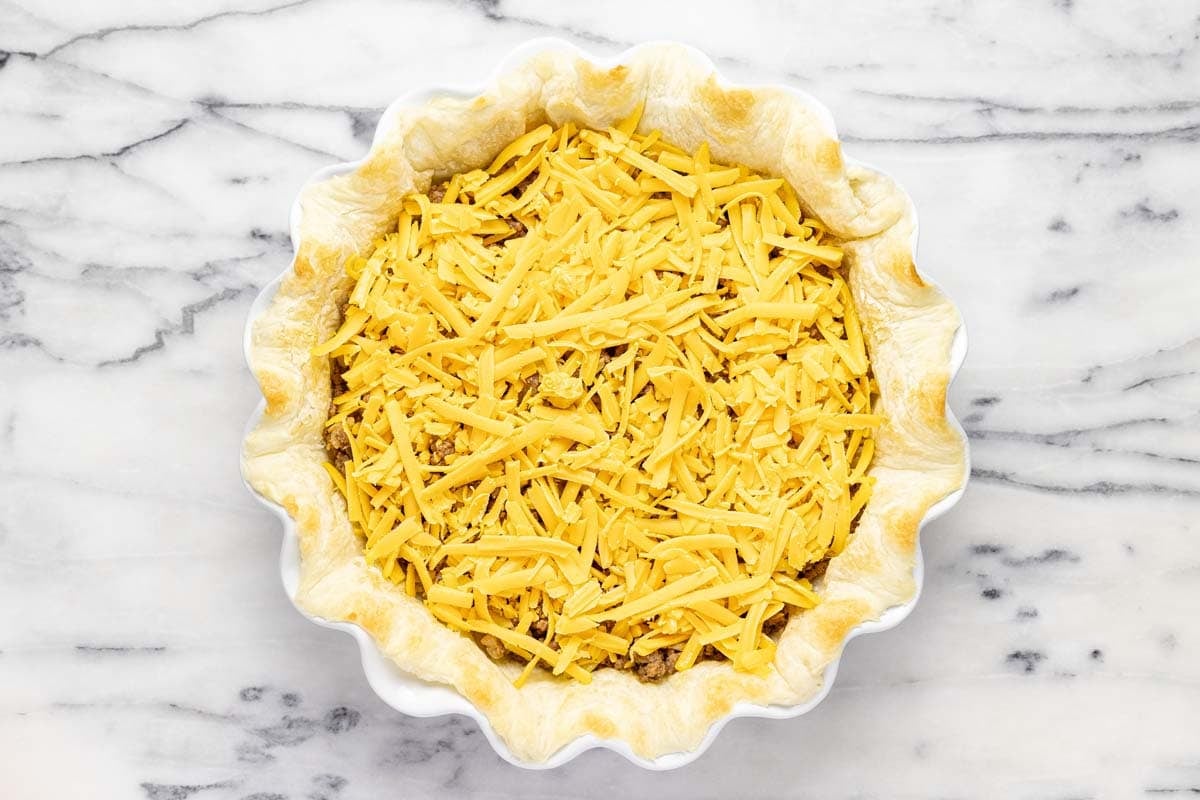 Shredded ground beef and shredded cheese in a cooked pie crust. 