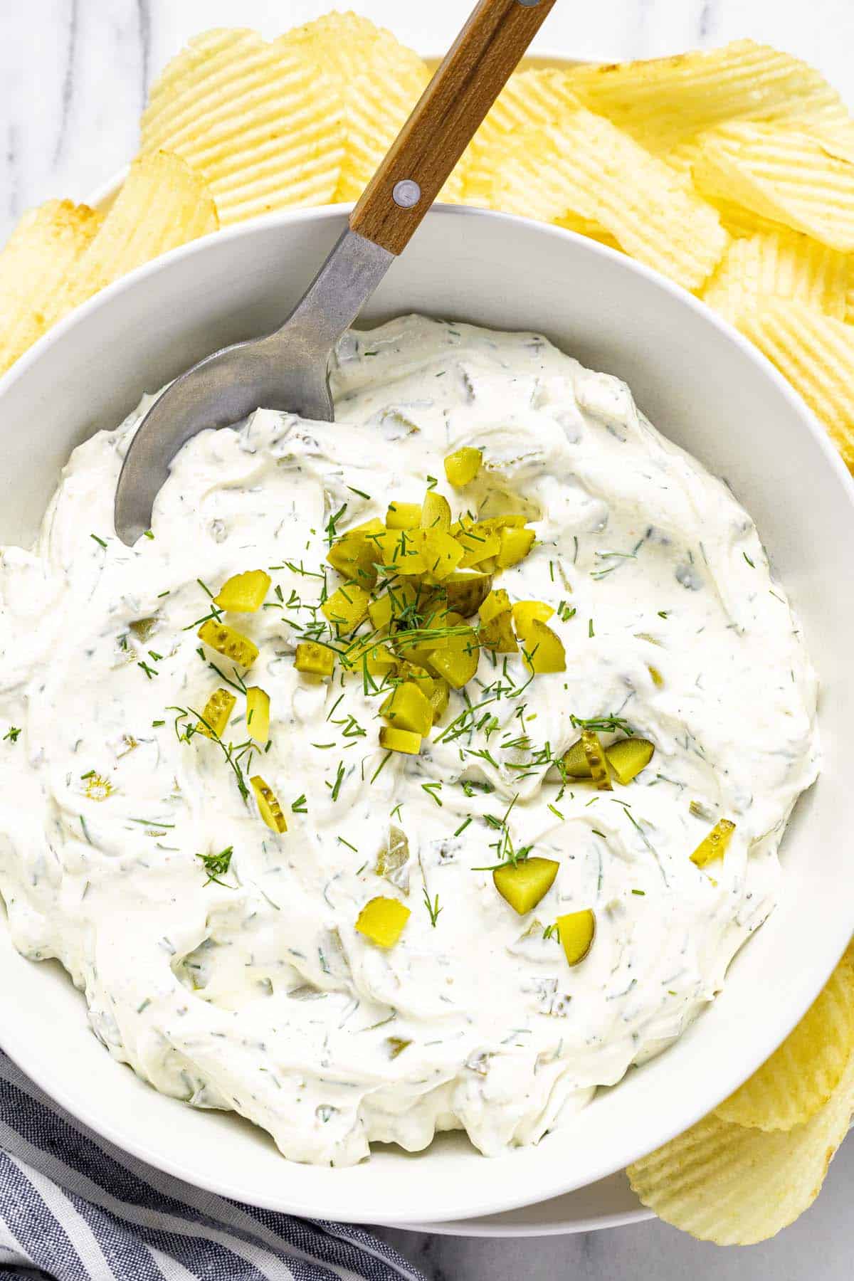 Bowl of dill pickle dip garnished with pickles and dill. 