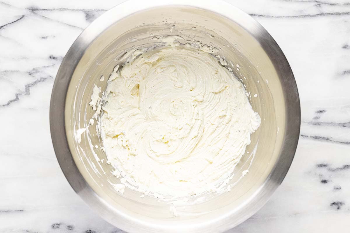 Metal bowl with spices, cream cheese, and sour cream mixed together. 