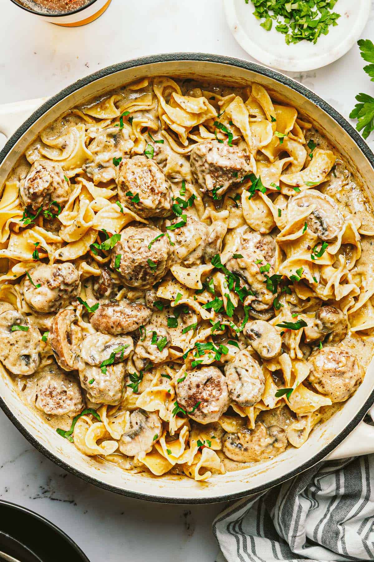 Large pan filled with creamy meatball stroganoff garnished with fresh parsley.