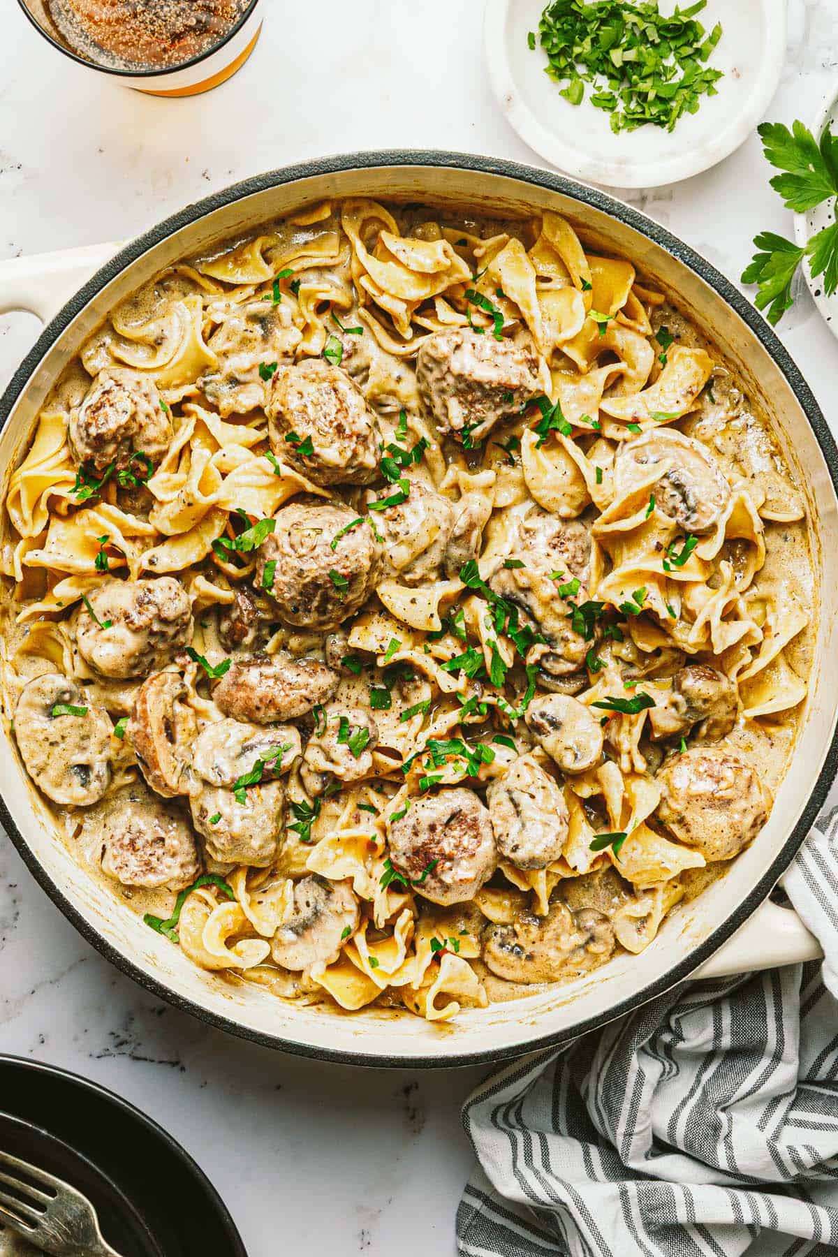 Large pan filled with creamy meatball stroganoff garnished with fresh parsley. 