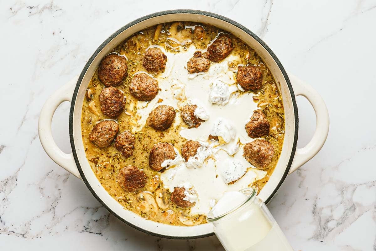 Heavy cream added to a large pot of mushroom meatball stroganoff. 