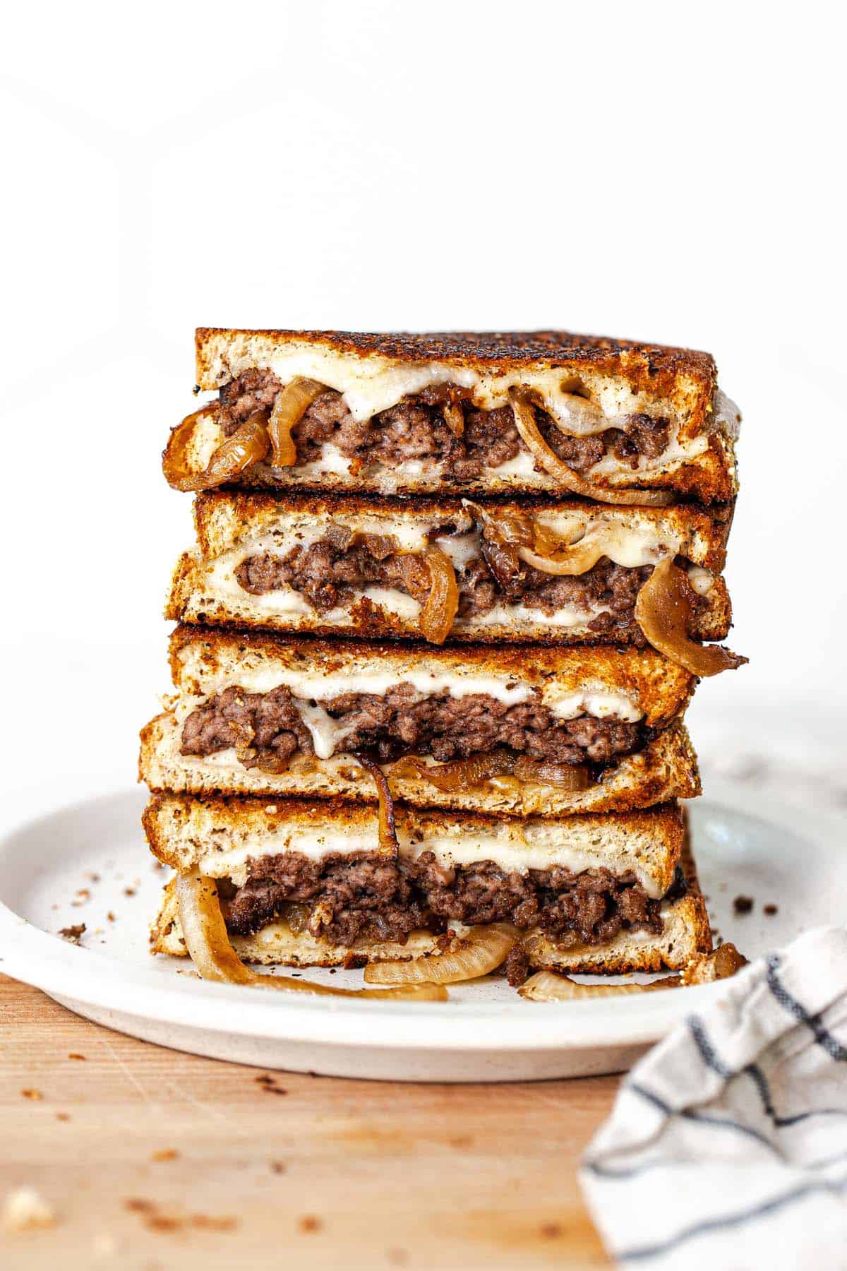 Two patty melts cut in half on a plate so you can see the inside of the melt.