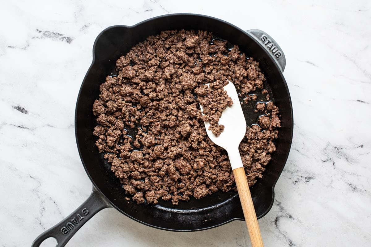 Large skillet with browned ground beef. 