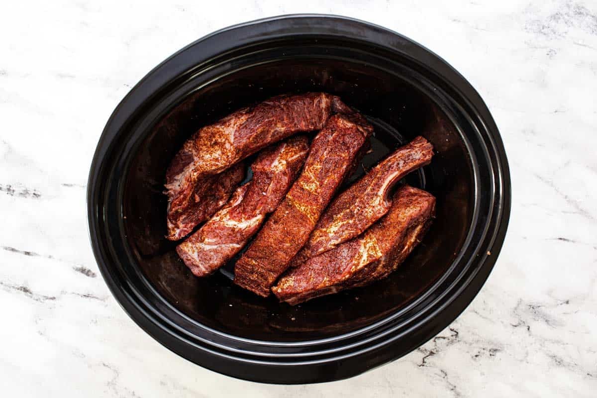 Seasoned pork ribs in a large slow cooker. 