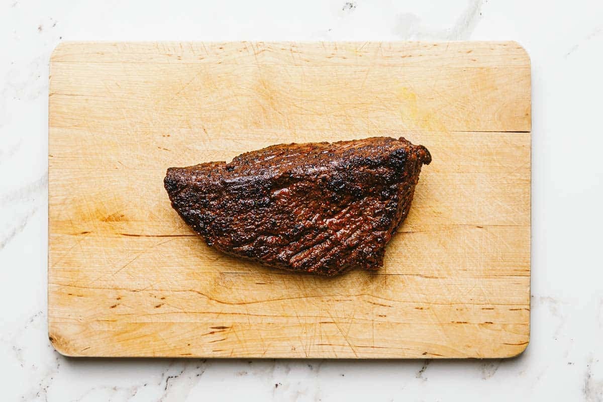 Seared steak on a large wooden cutting board. 