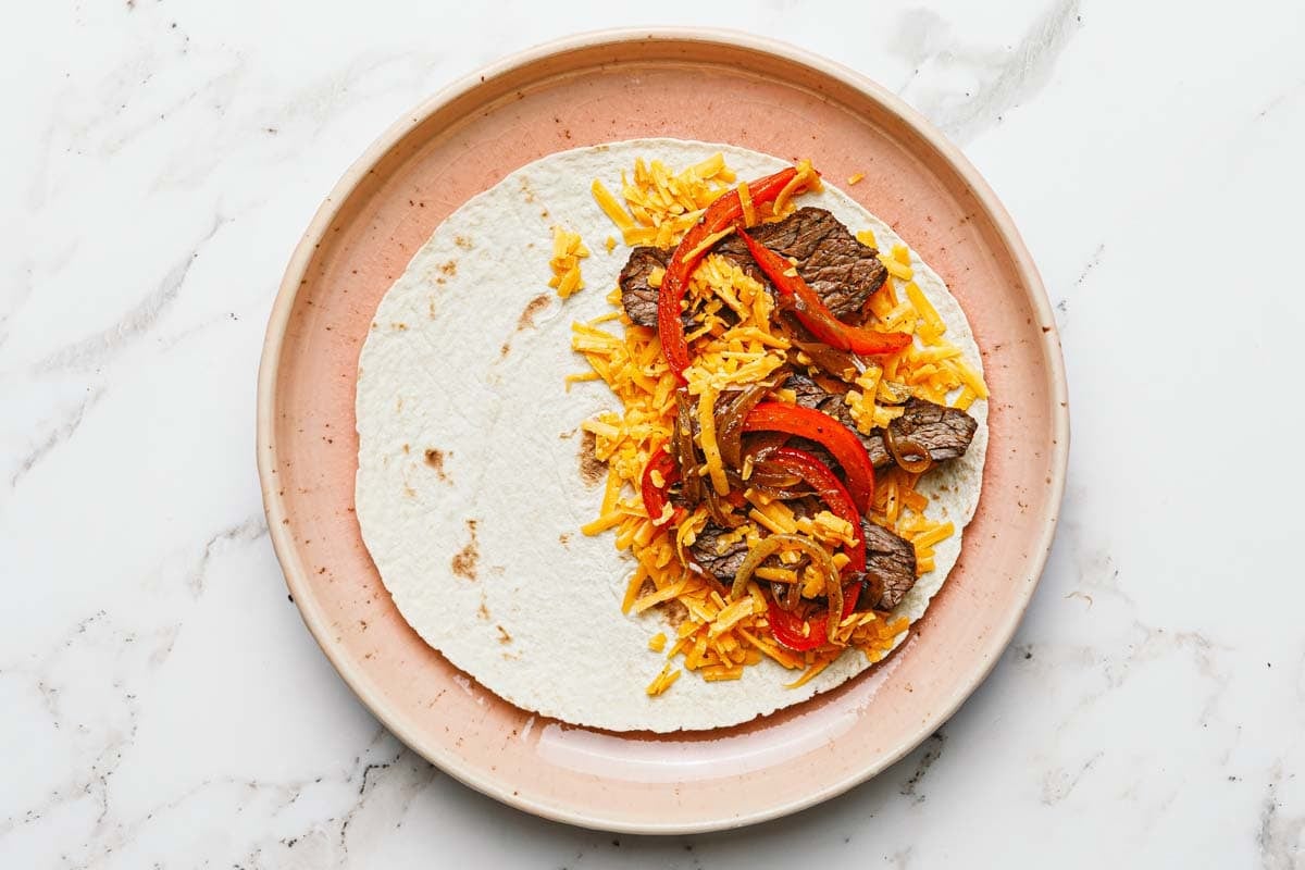 Tortilla topped with cheese, sliced steak, and sauteed veggies. 