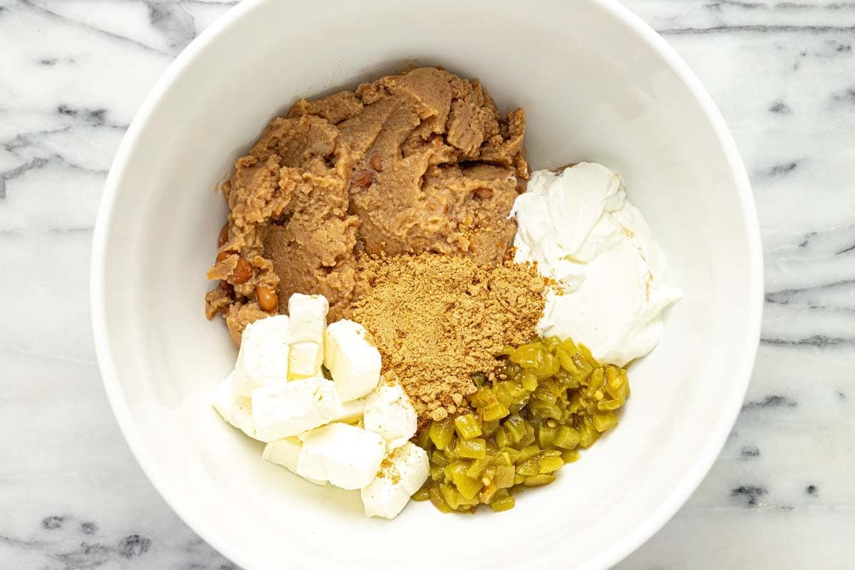 Large bowl with ingredients to make bean dip. 