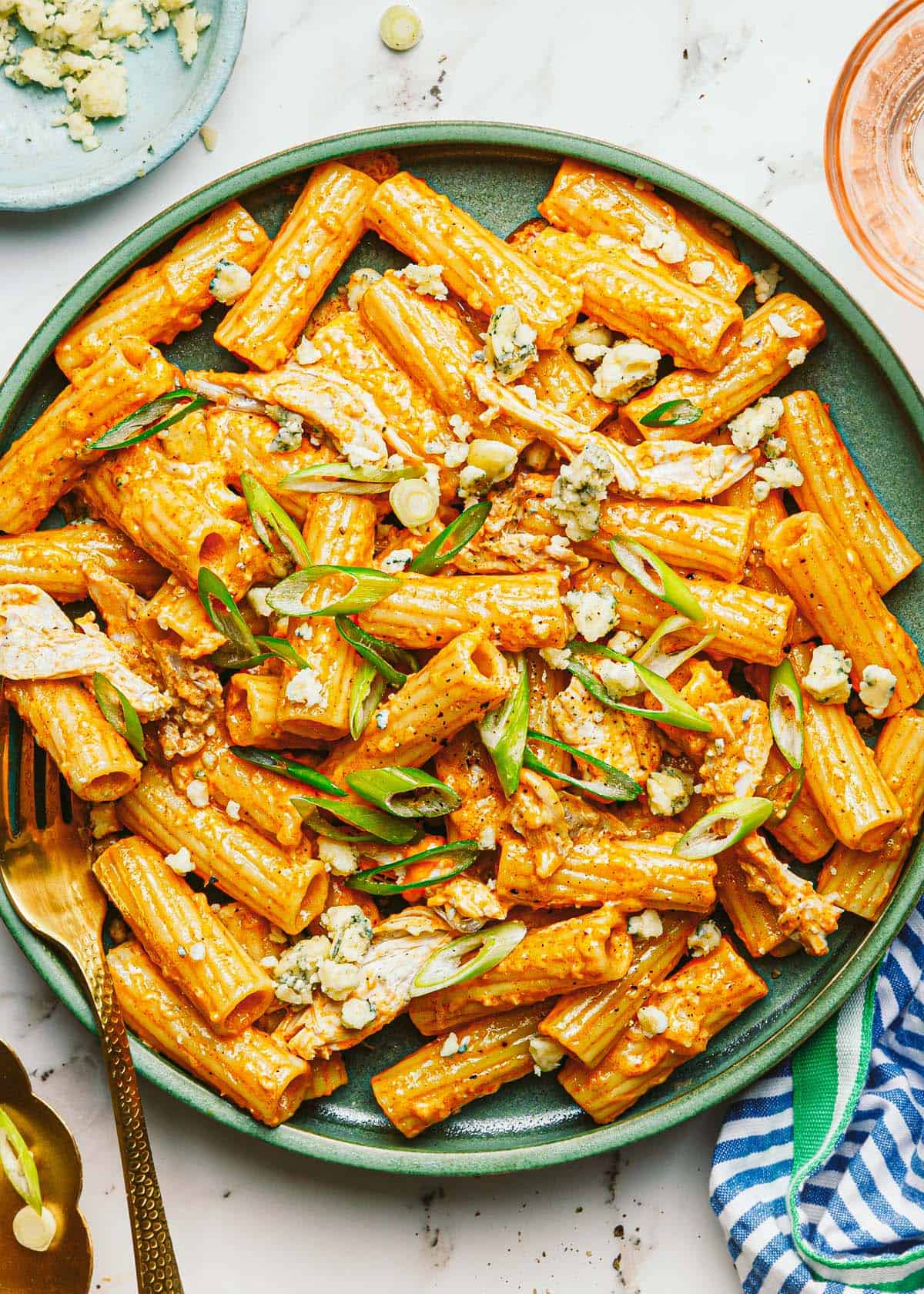 Plate of buffalo chicken pasta garnished with blue cheese and green onion. 