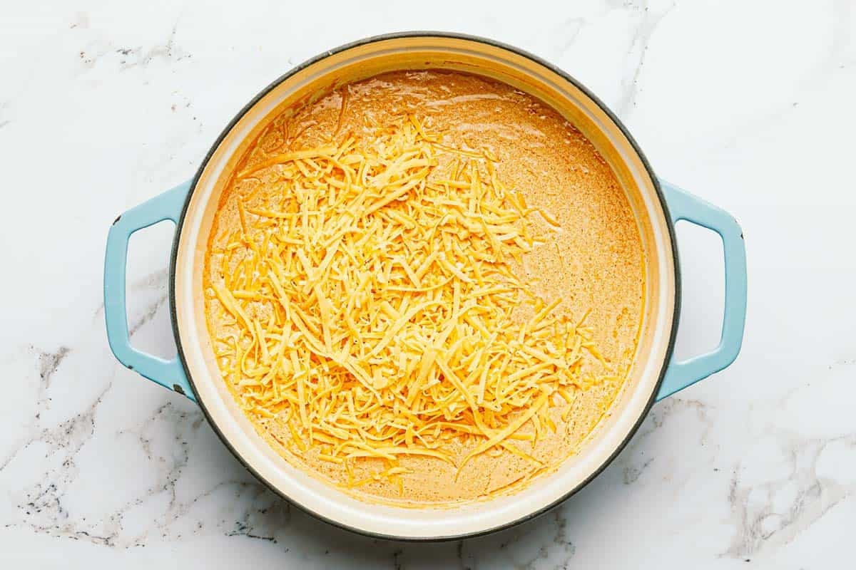 Shredded cheese in a pan of creamy buffalo sauce. 