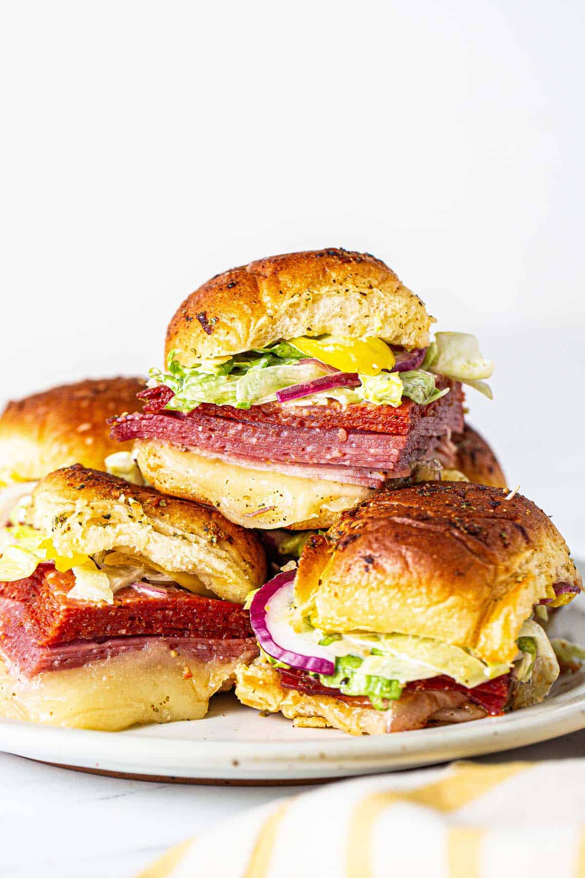 Italian sliders cut apart and stacked on a serving platter. 
