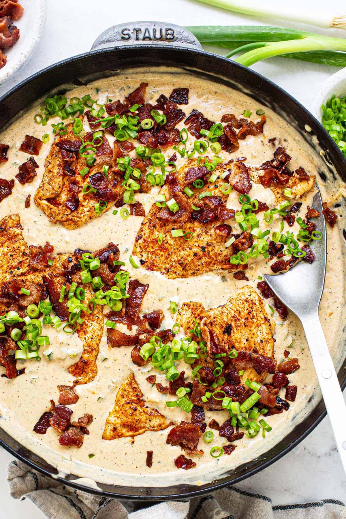 Large pan filled with creamy jalapeno popper chicken garnished with green onion. 