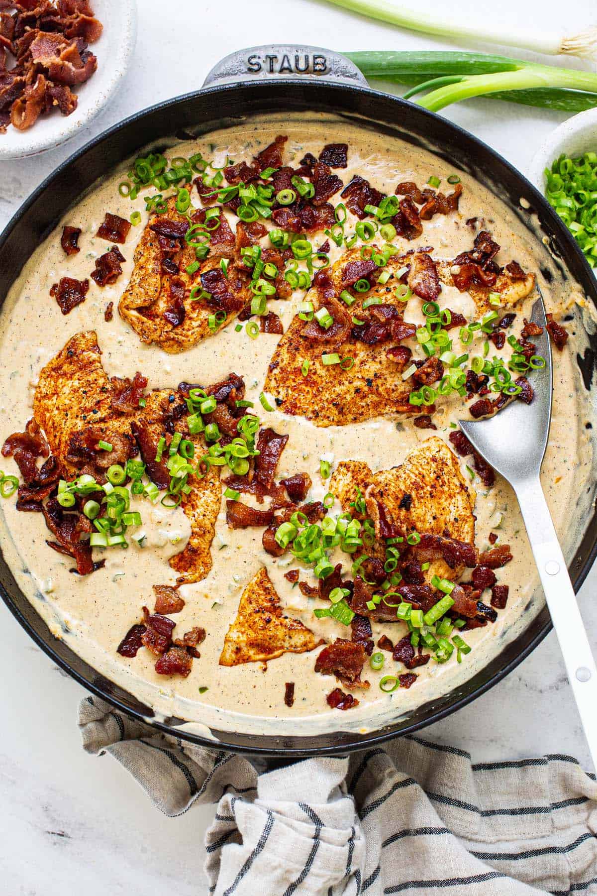 Large pan filled with creamy jalapeno popper chicken garnished with green onion. 