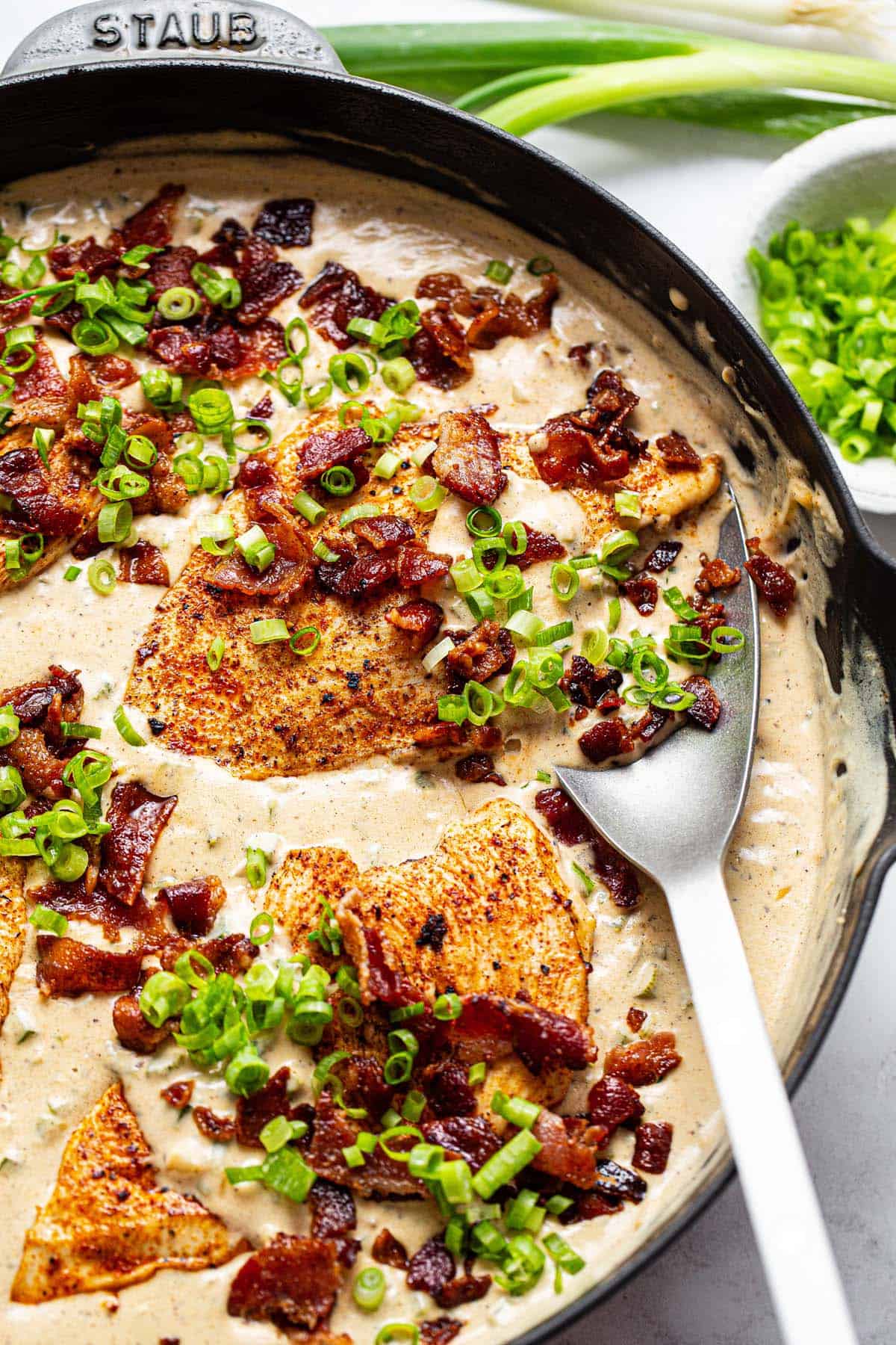 Large pan filled with creamy jalapeno popper chicken garnished with green onion. 