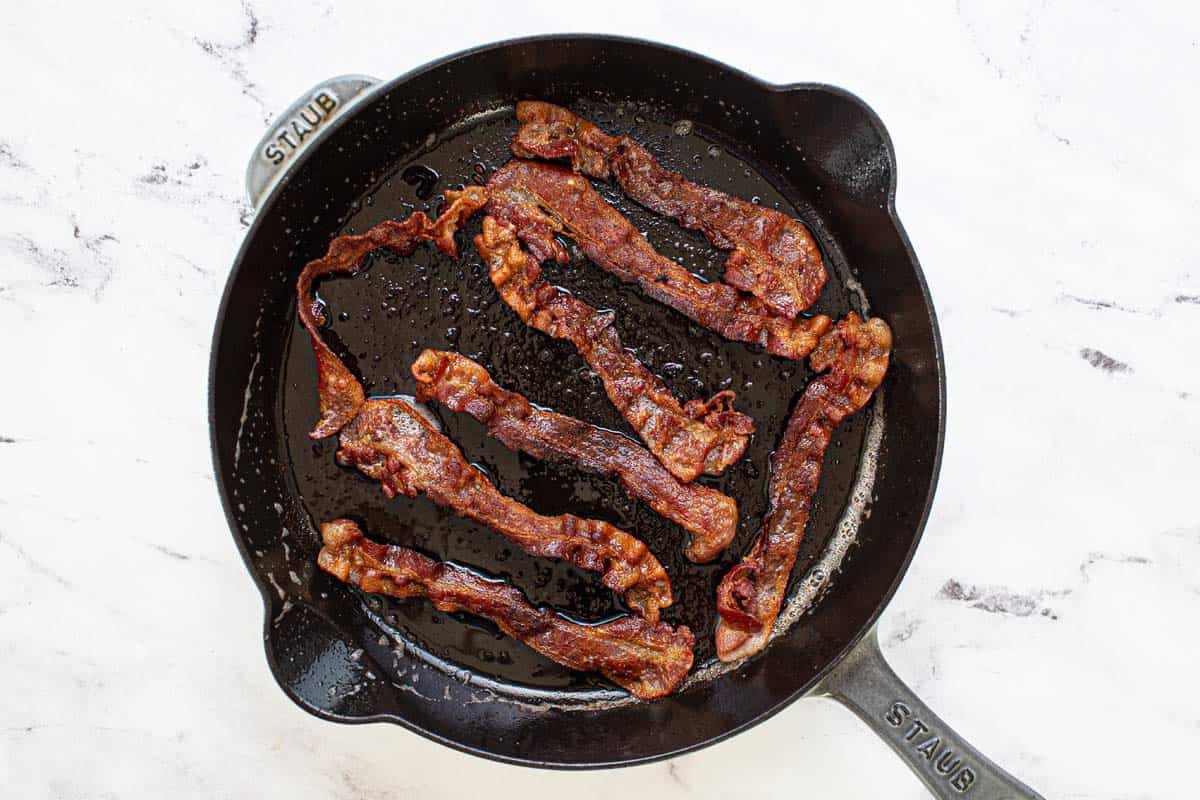Crispy cooked bacon in a large cast iron pan. 