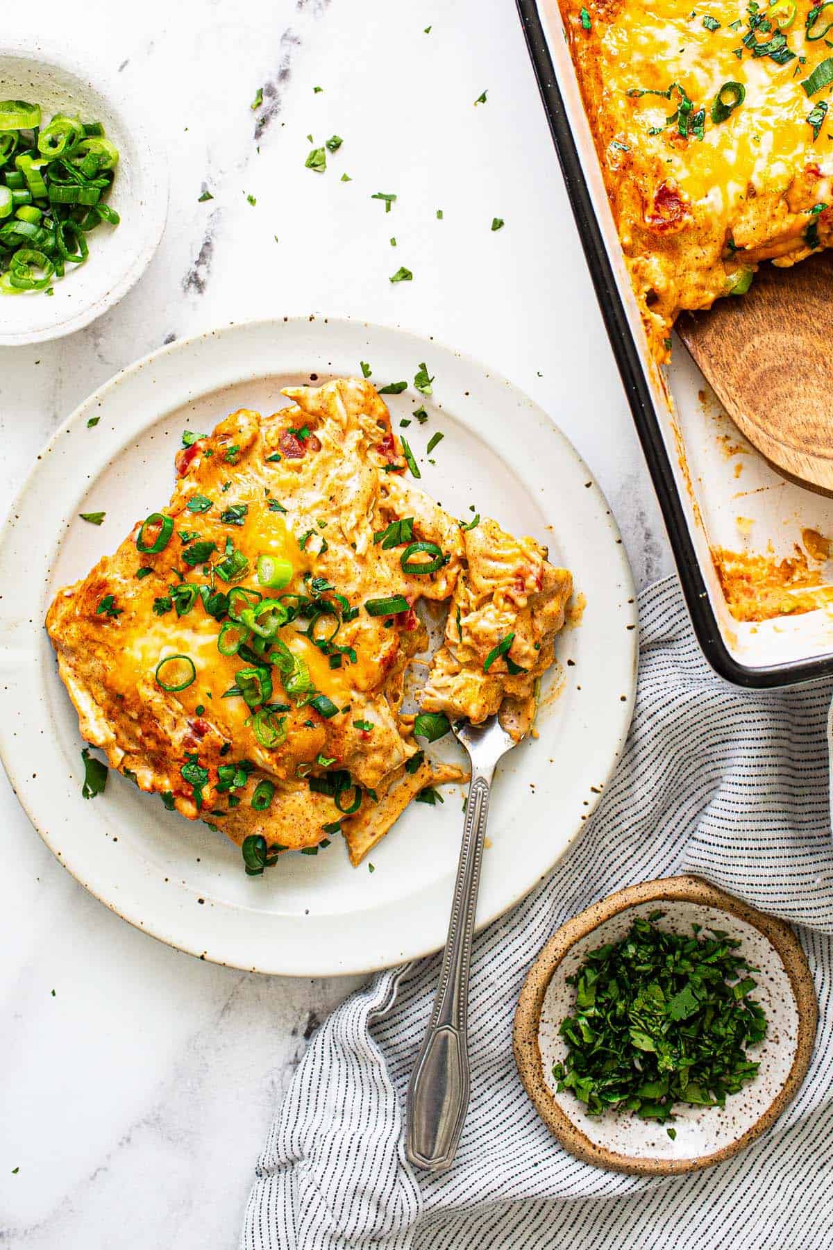 A serving of king ranch chicken casserole on a plate garnished with green onion. 