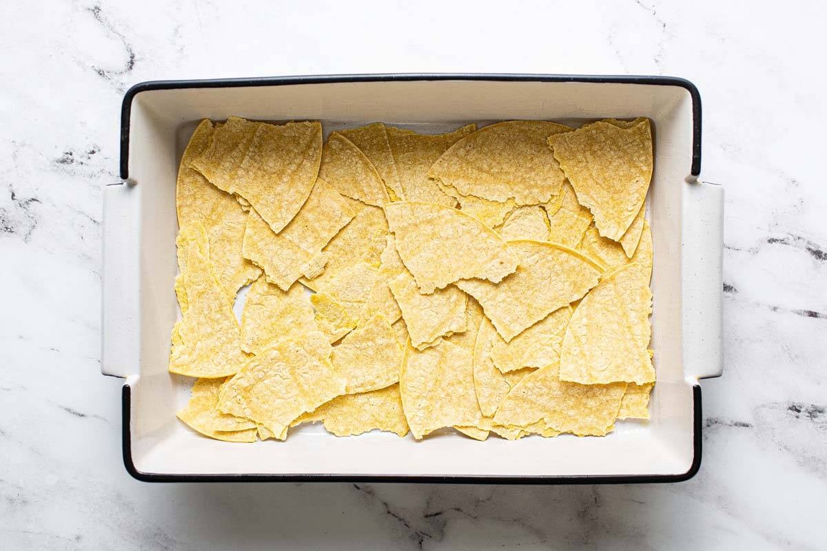Corn tortillas torn and layered in the bottom of a 9x13 baking dish. 