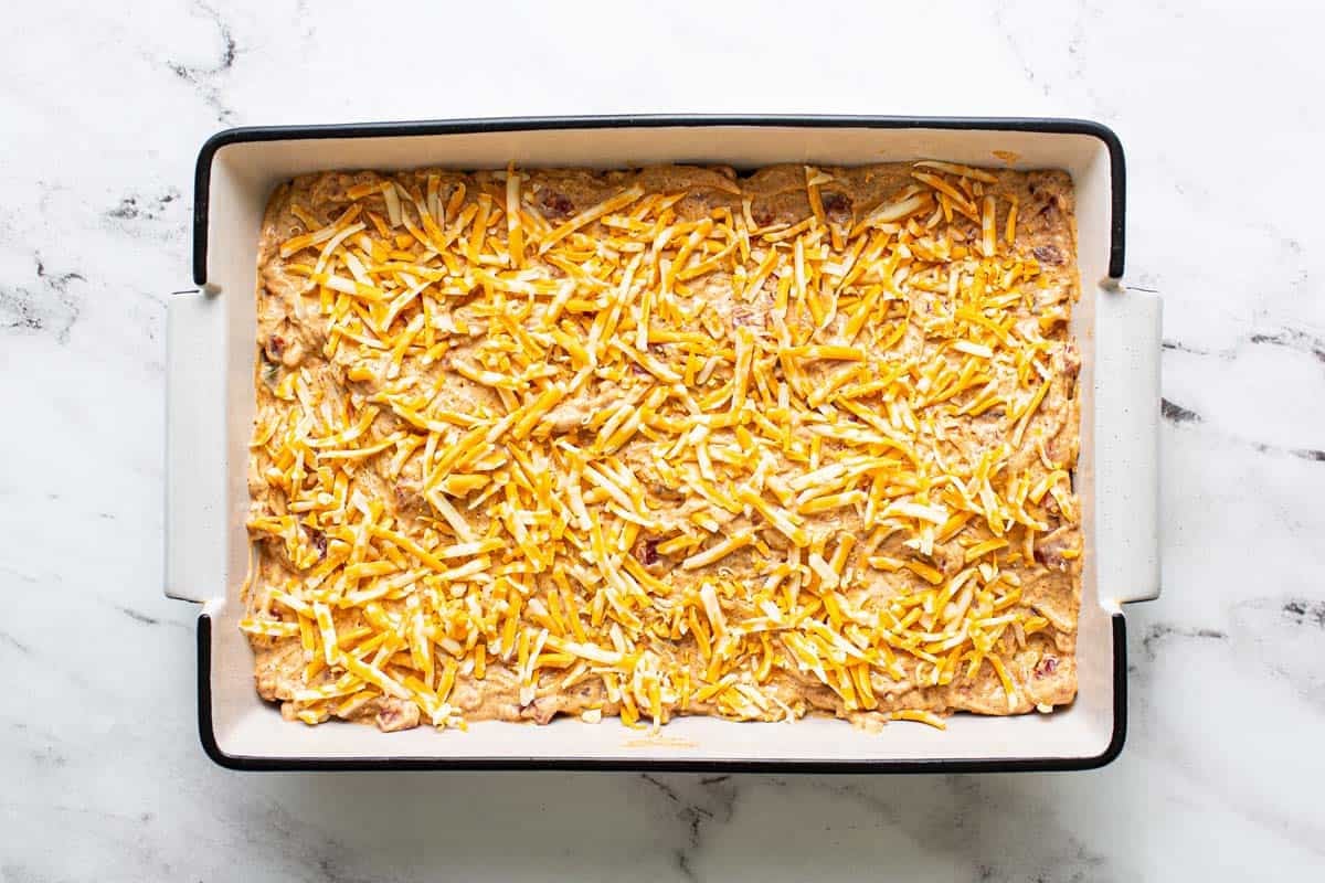 Cheesy chicken filling and shredded cheese added to the baking dish. 