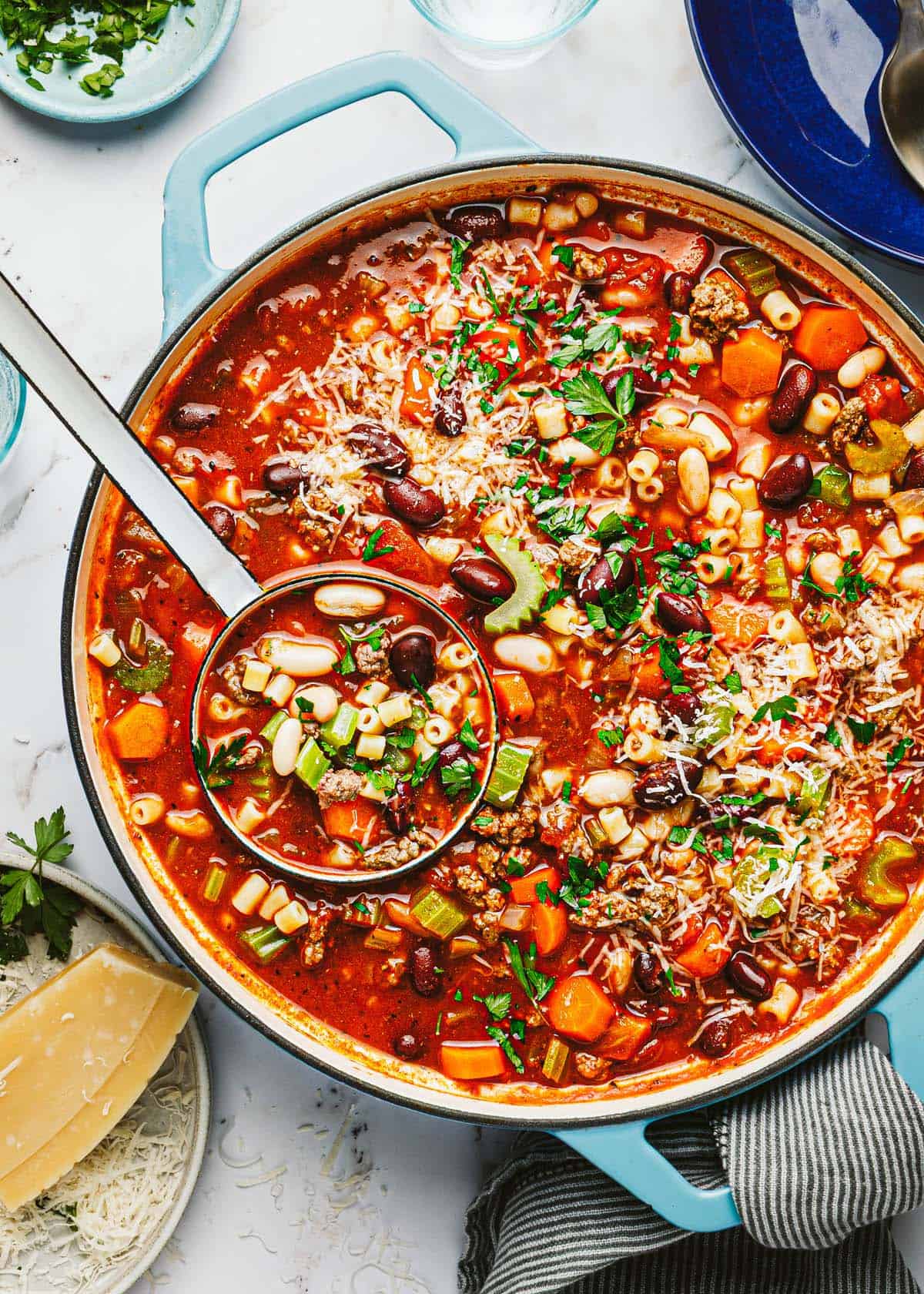 Large pot filled with Italian pasta fagioli garnished with Parmesan. 