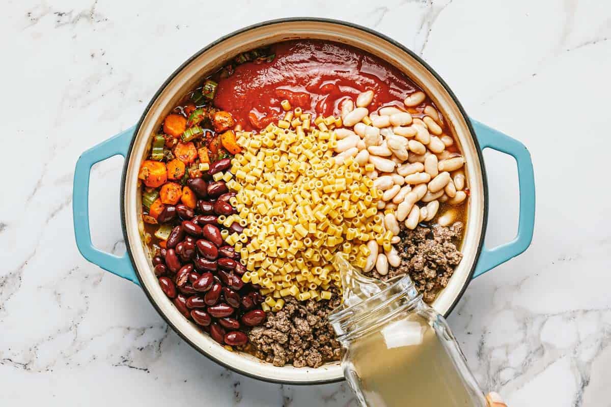 Large pot filled with sauteed veggies, beans, ground beef, tomato sauce, and pasta. 