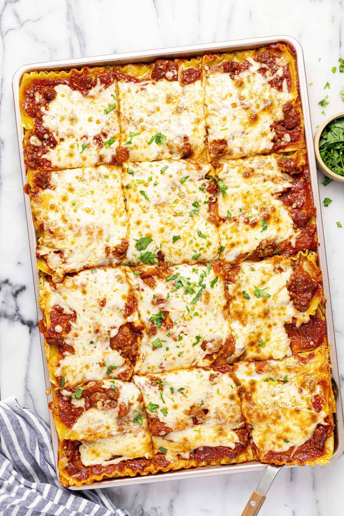 Sheet pan filled with homemade lasagna garnished with fresh parsley. 