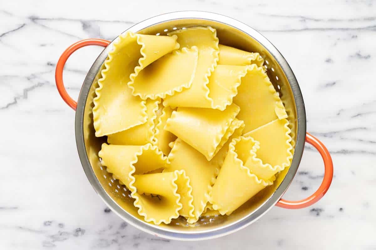 Boiled lasagna noodles in a strainer. 