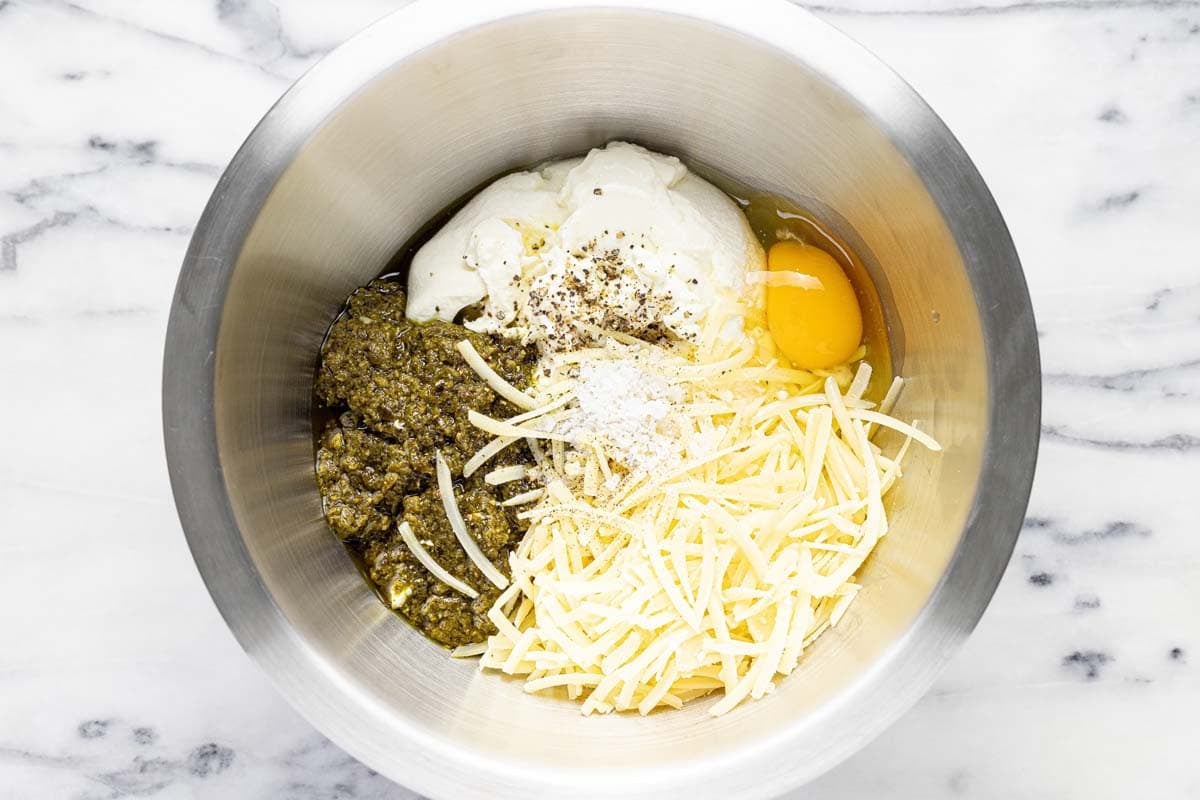 Bowl with cheese, pesto, egg, and ricotta for filling lasagna. 