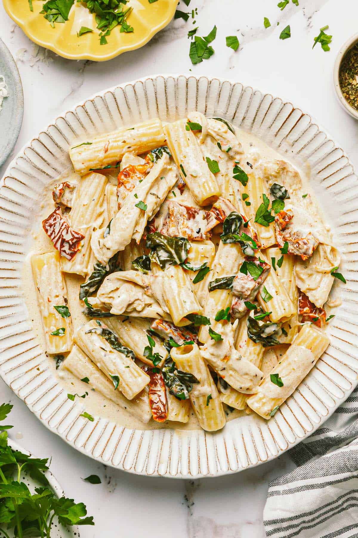 Large plate filled with creamy Tuscan chicken pasta garnished with parsley.
