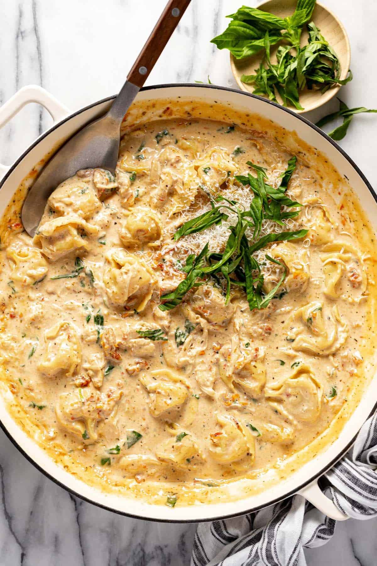 Creamy Tuscan chicken tortellini in a large pan. 