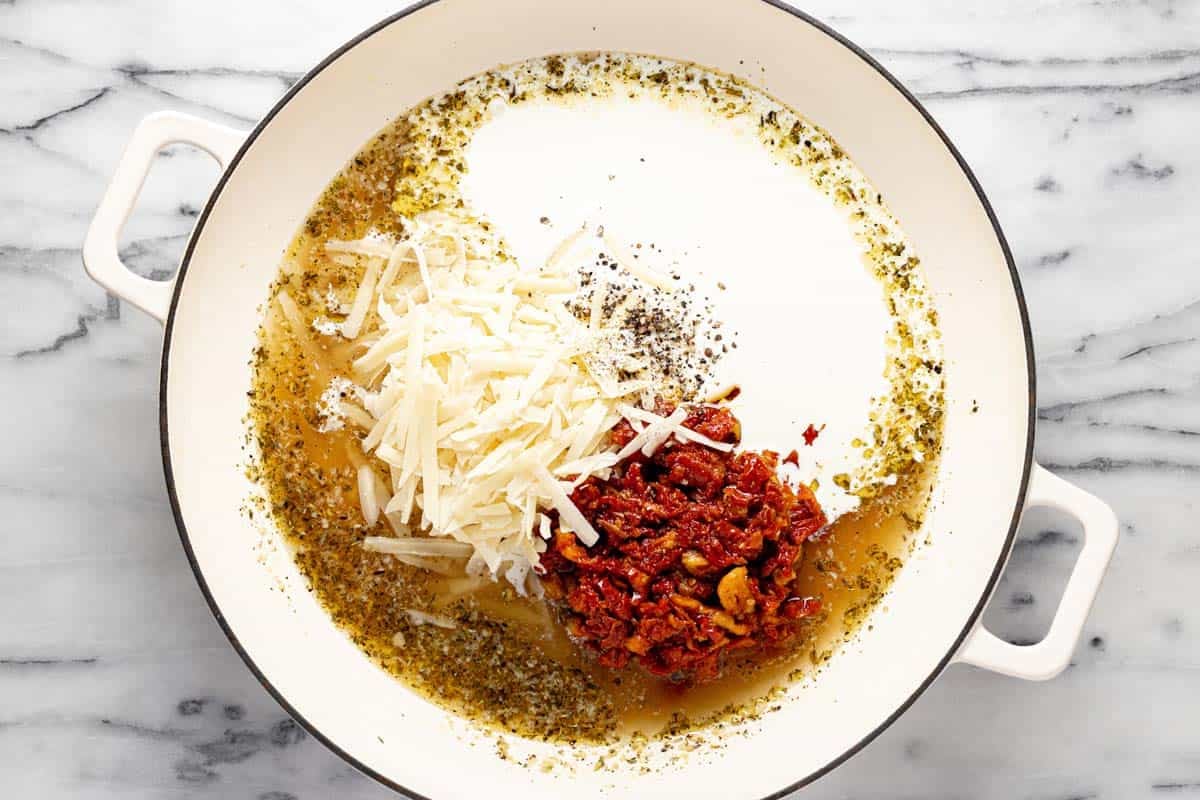 Large pan filled with Parmesan, heavy cream, broth, and sun-dried tomatoes to create a sauce. 