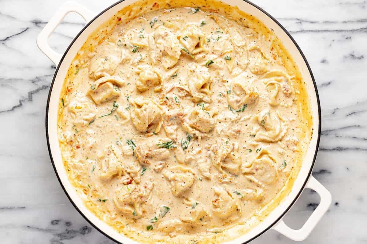 Creamy Tuscan chicken tortellini in a large pan. 