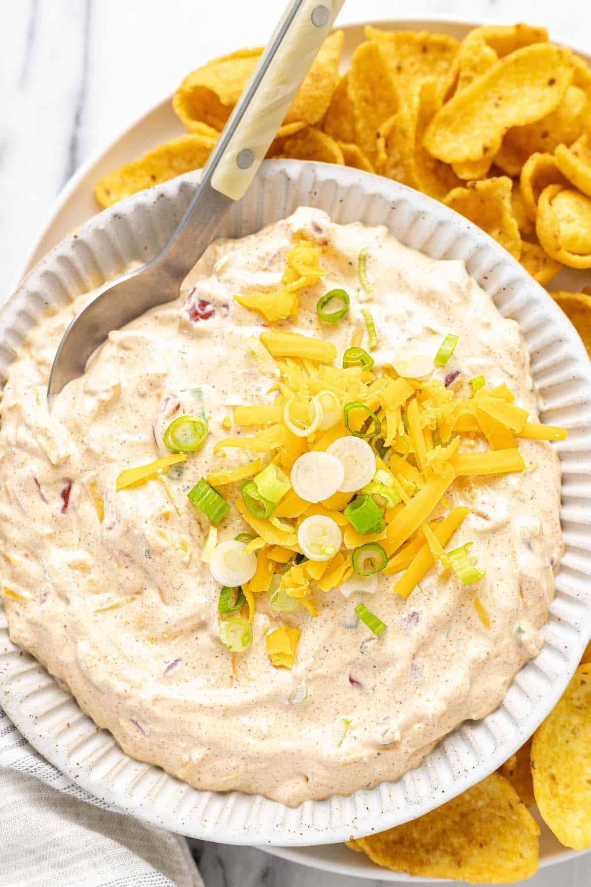 Bowl of boat dip on a platter of Fritos and potato chips. 