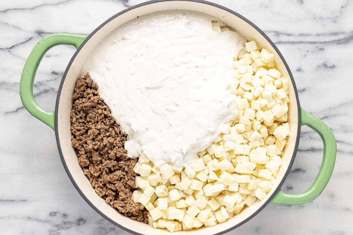 Ground beef, frozen potatoes, and creamy soup mixture in a large pan. 