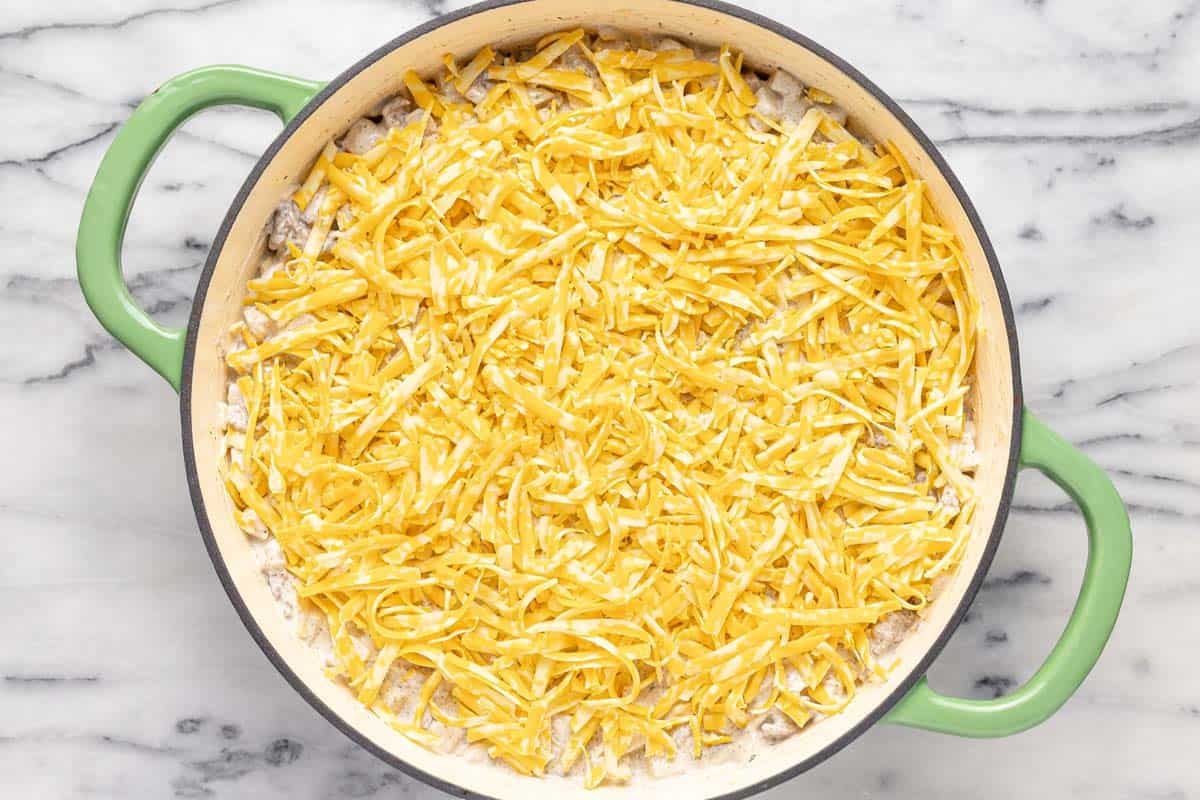 Shredded cheese on top of a hamburger and potato casserole. 