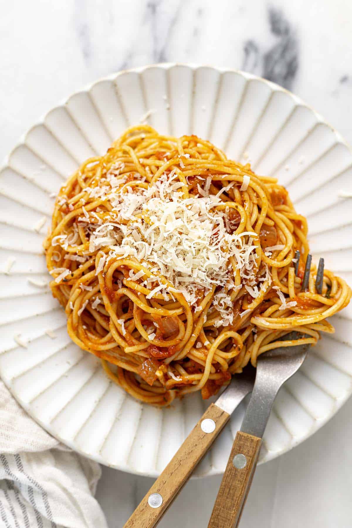 Plate of spaghetti tossed in sauce and topped with Parmesan. 