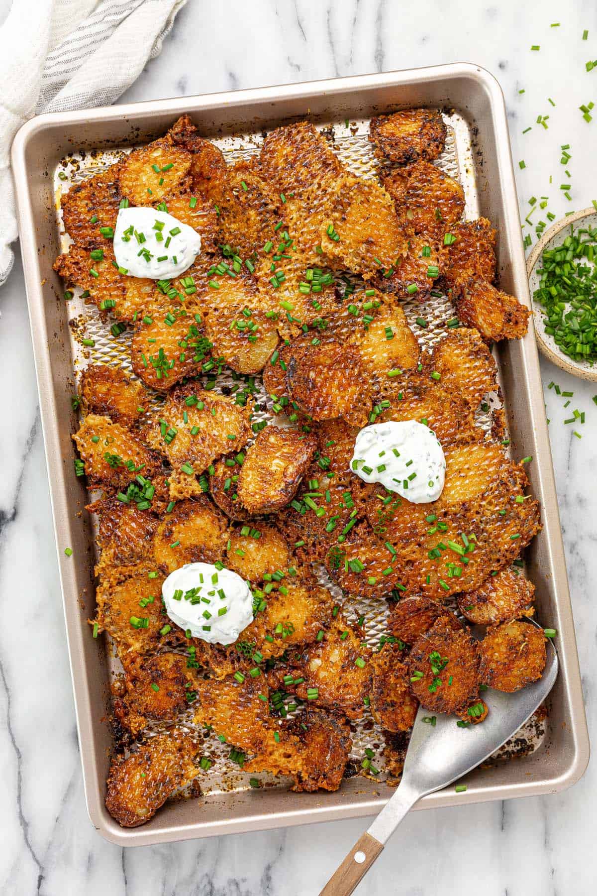 Baking sheet filled with crispy roasted red potatoes with chives and sour cream. 