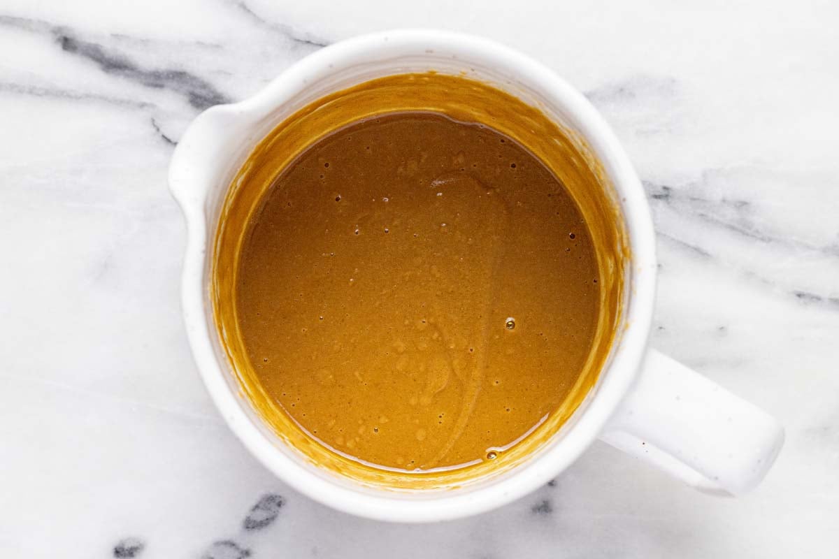 Creamy peanut marinade in a large measuring cup. 