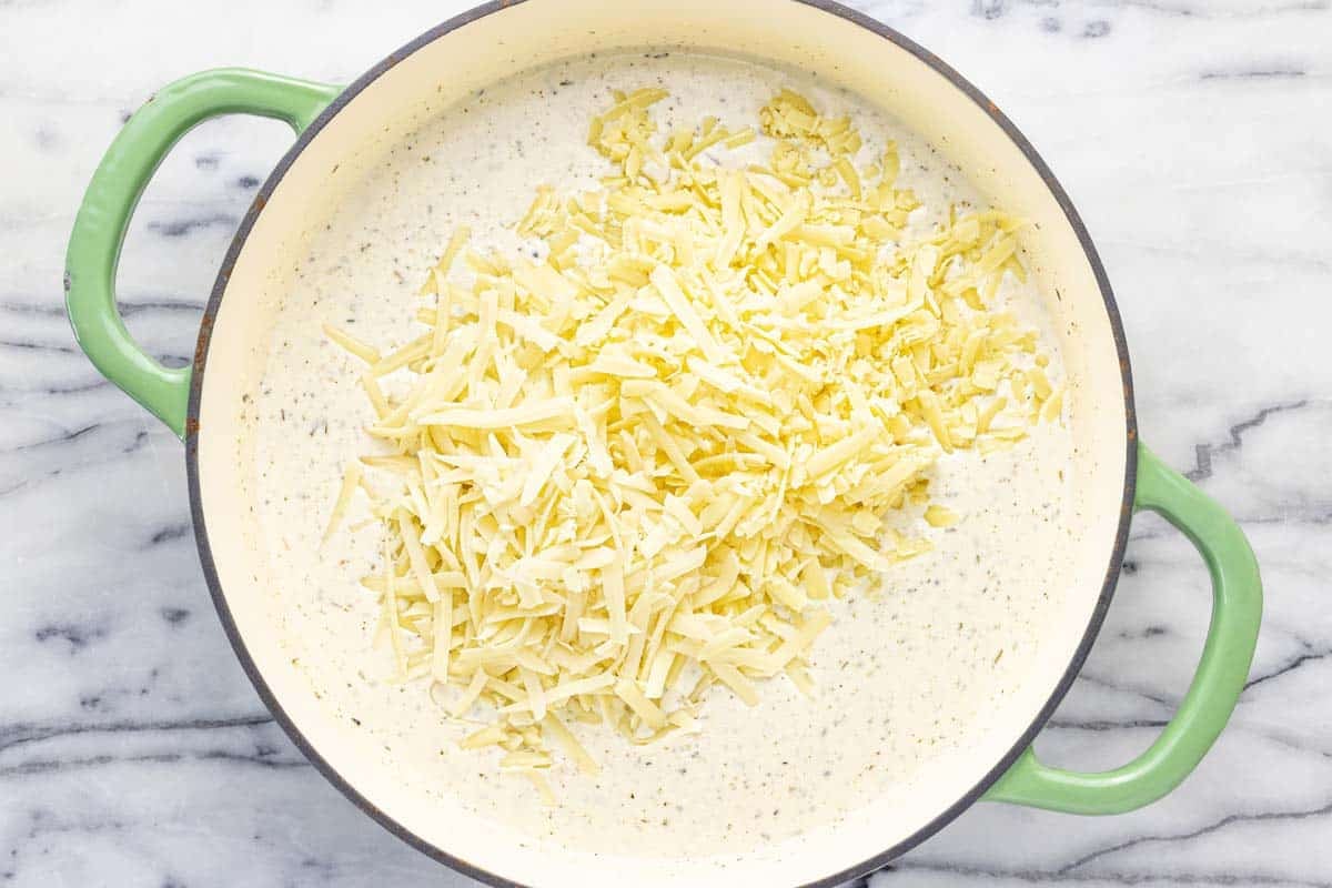 Pan filled with creamy au gratin sauce with shredded cheese added. 
