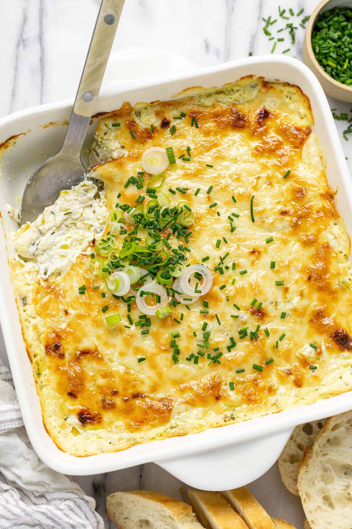 Baking dish filled with pepperoncini dip garnished with chives and green onion.